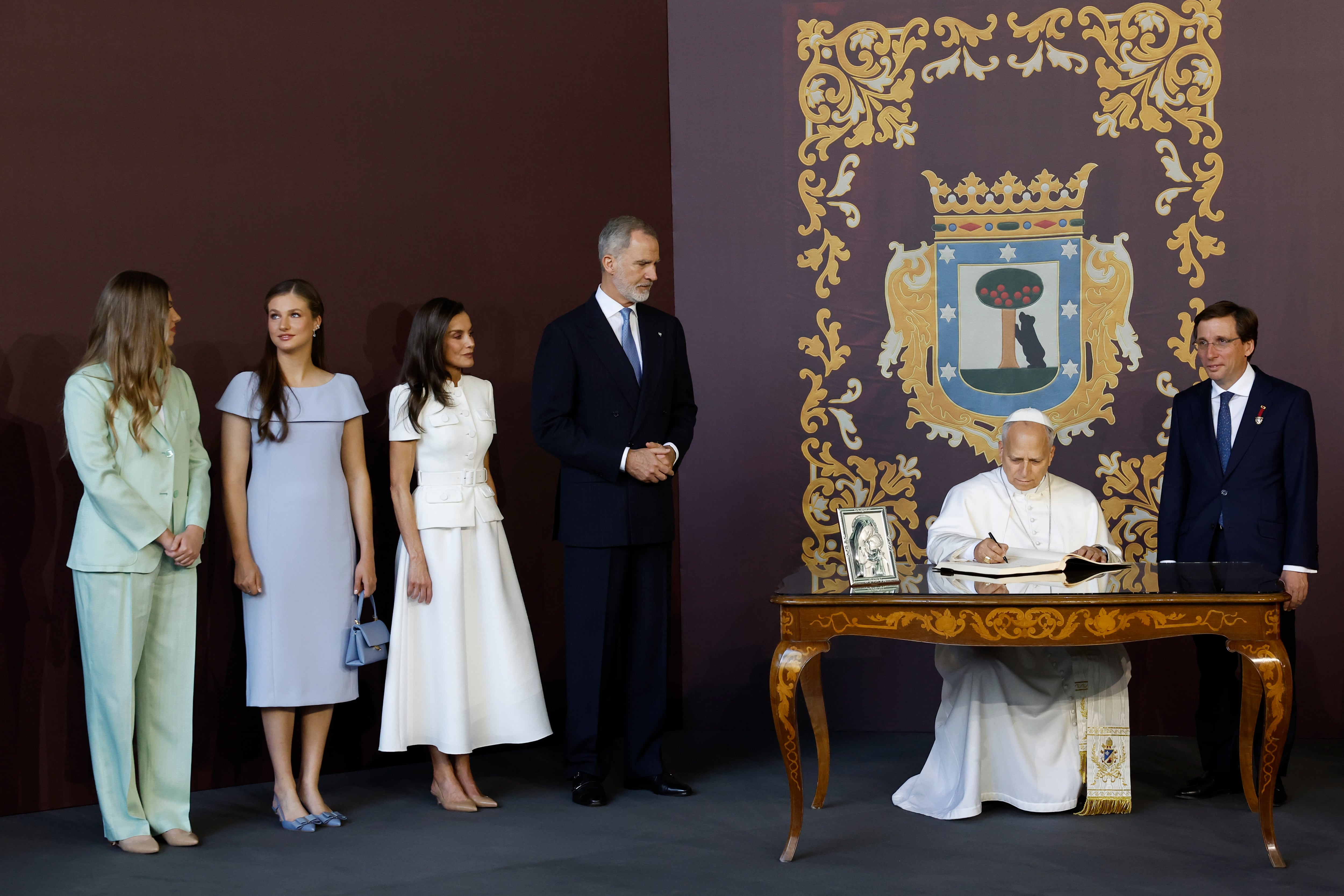 El papa León XIV firma en el libro de invitados junto al alcalde de Madrid, José Luis Martínez-Almeida (d), el rey Felipe VI, la reina Letizia, la princesa Leonor y la infanta Sofía antes de la misa del Corpus Christi en Cibeles. (EFE/ Chema Moya)