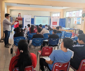 Jóvenes sentados en un aula, con un hombre y una mujer al frente. Se ve una pantalla con códigos QR y banners de "Camino al empleo" y "Lima Centro" en el fondo