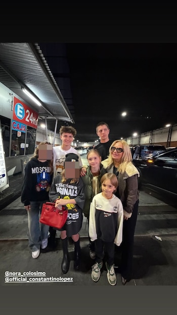 Wanda Nara posa con cinco de sus hijos en una salida nocturna, de pie en un exterior con iluminación artificial, un cartel de "CAJA" y coches de fondo