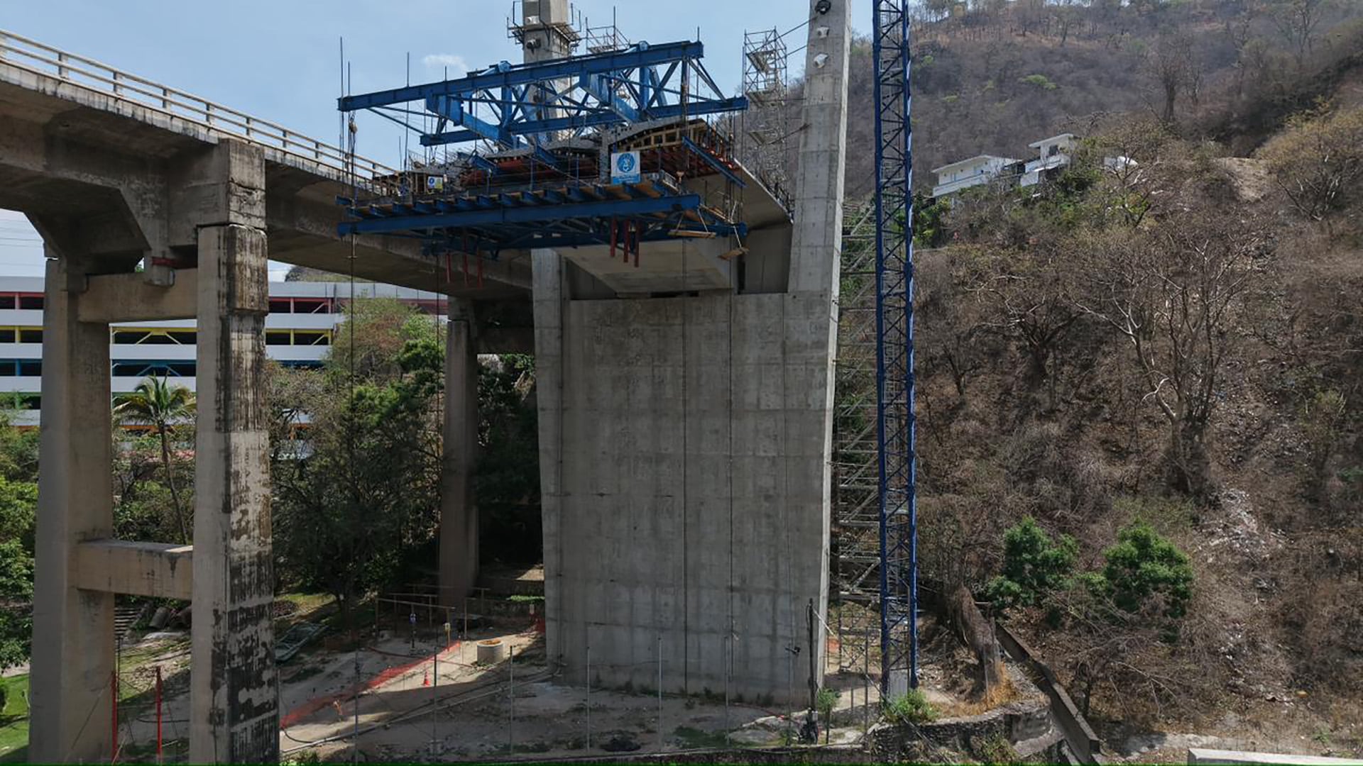 Una vista aérea muestra el progreso en la construcción de un nuevo tramo de puente de hormigón, con una estructura de viga metálica azul en posición para la siguiente fase de montaje. (Ministerio de Comunicaciones, Infraestructura y Vivienda)
