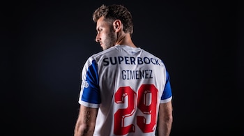 Un hombre de espaldas viste una camiseta deportiva blanca con azul que lleva el nombre Gimenez, la marca Super Bock y el número 29 en rojo.