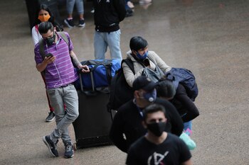 Passengers wearing protective masks line