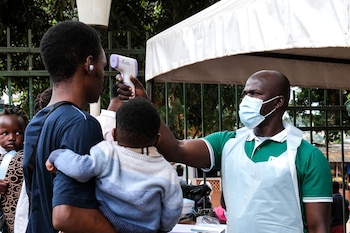 Un funcionario de salud utiliza un termómetro para tomar la temperatura a las personas frente al Hospital Musulmán de Kibuli, en Kampala, Uganda, el sábado 16 de mayo de 2026. (AP Foto/Hajarah Nalwadda)