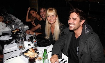 Grecia Colmenares, Matías Alé y otros en una mesa de restaurante, sonriendo. Hay botellas de refresco, vasos y pan sobre el mantel blanco