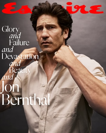 Jon Bernthal, hombre caucásico de pelo oscuro y barba corta, con camisa beige abierta, ajusta su cuello mirando fijamente al frente en una portada