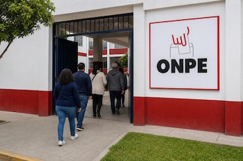 Grupo de personas de espaldas entrando por un portón a un edificio que tiene un cartel con el logo de ONPE.