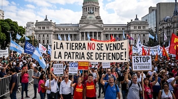 Manifestantes sostienen pancartas y banderas argentinas frente al edificio del Congreso de la Nación Argentina.