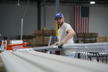 Un trabajador levanta una viga de aluminio en la planta de The Luxury Pergola, una empresa que fabrica pérgolas de aluminio, el viernes 20 de febrero de 2026, en Noblesville, Indiana (AP Foto/Obed Lamy)