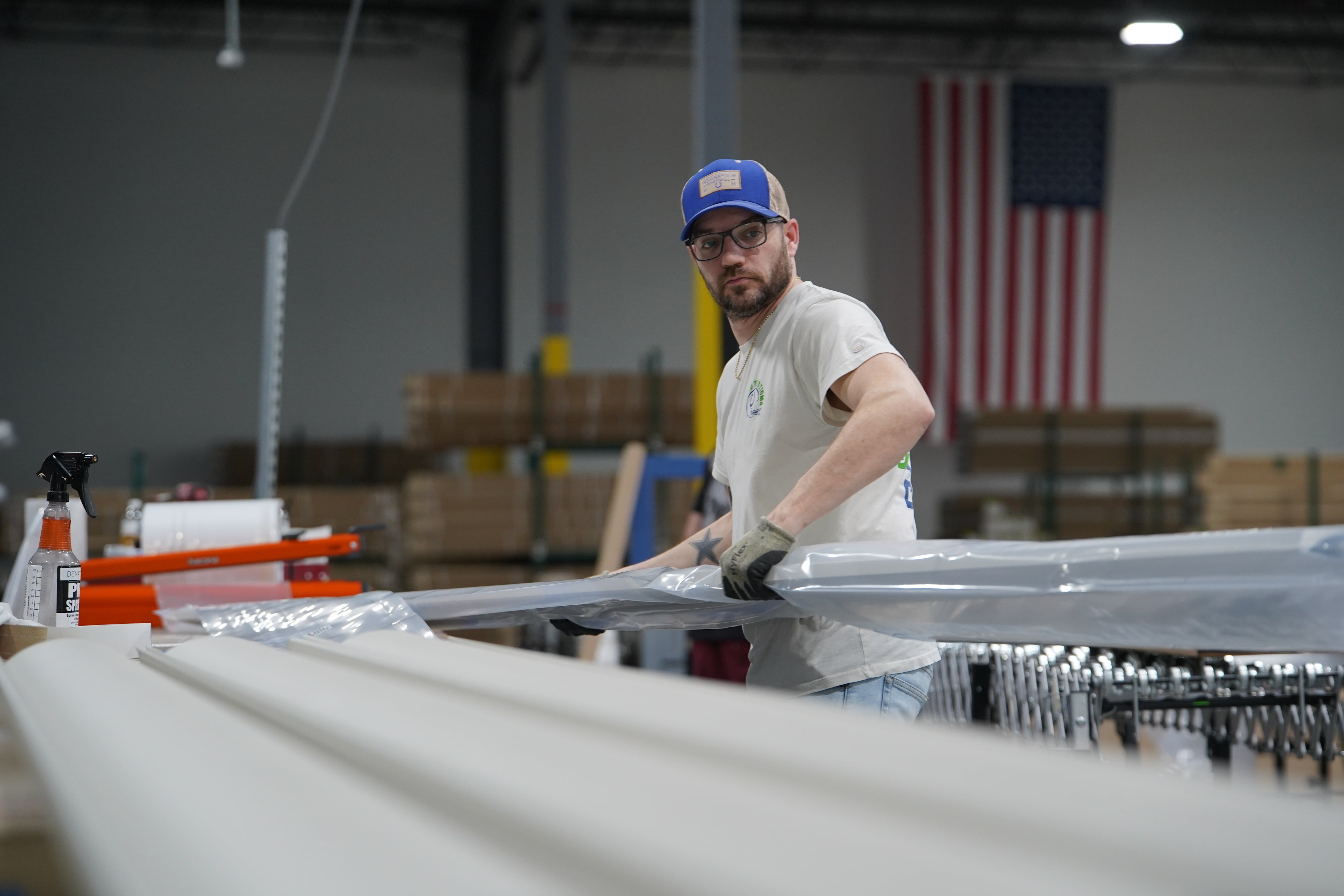 Un trabajador levanta una viga de aluminio en la planta de The Luxury Pergola, una empresa que fabrica pérgolas de aluminio, el viernes 20 de febrero de 2026, en Noblesville, Indiana (AP Foto/Obed Lamy)