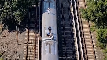 Personas viajan en el techo de un tren en movimiento - VisualesIA ScribNews
