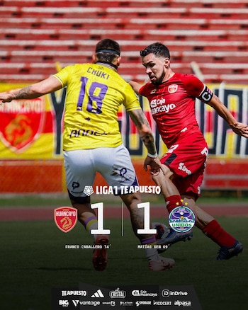 Dos futbolistas en acción durante un partido en un estadio. Uno con camiseta amarilla y el número 18, y otro con camiseta roja. Un marcador digital muestra '1-1'