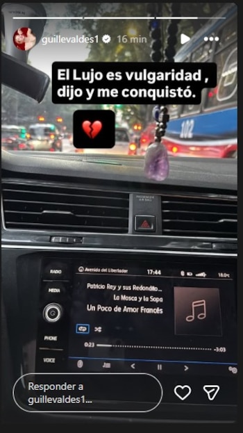 Vista interior de un coche en el tráfico mostrando una historia de Instagram de Guillermina Valdés con una cita y un reproductor de música tocando una canción de rock
