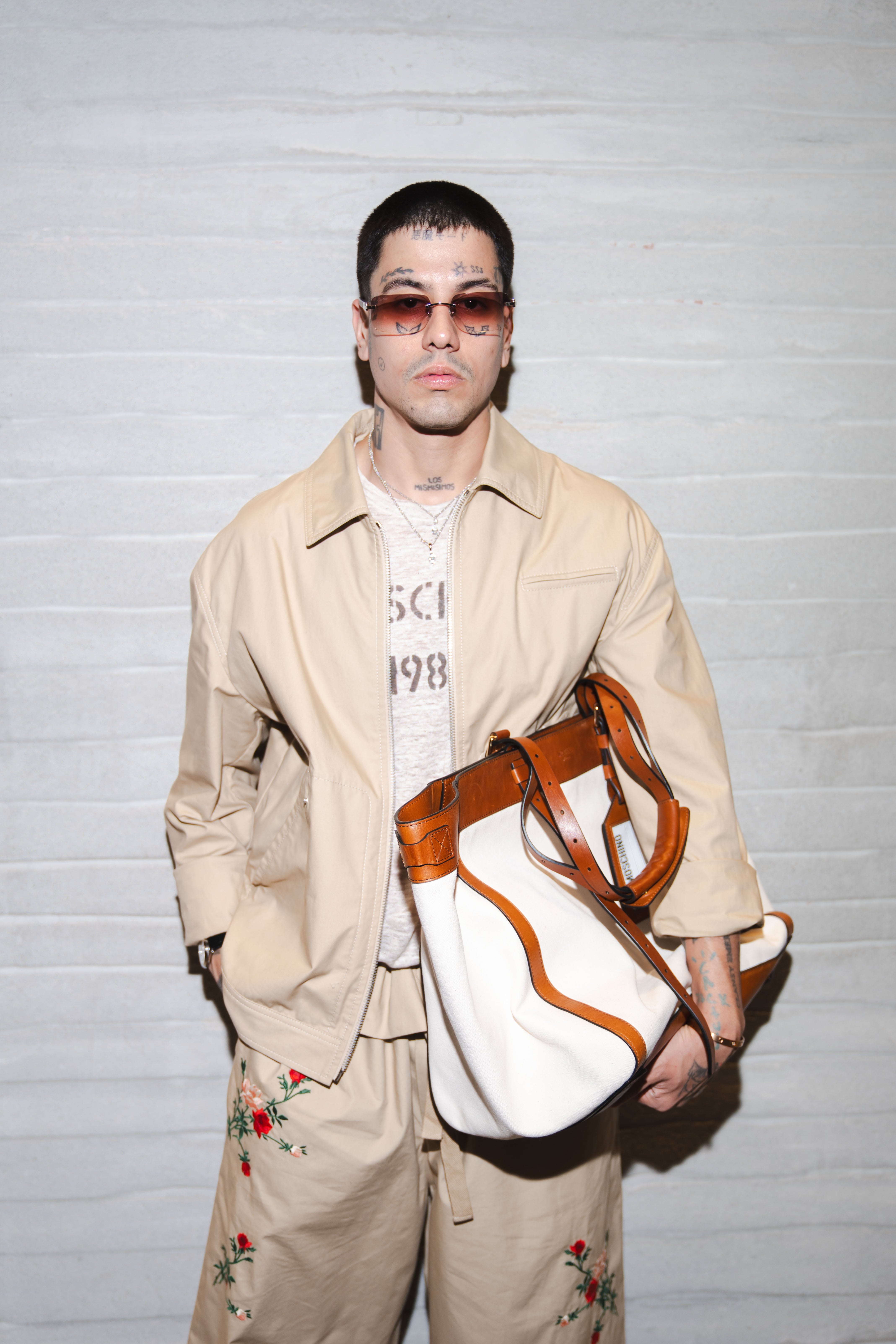 El artista Duki posa con un conjunto beige bordado y un bolso Moschino durante la Semana de la Moda de Milán, reafirmando su presencia en el mundo de la moda