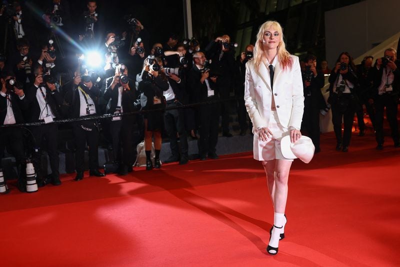 El blazer y la corbata se reinventan en clave femenina, con short y detalles teatrales en la pose y el peinado (REUTERS)