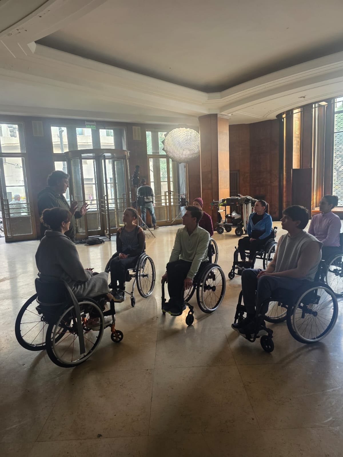Benjamín Vicuña conversa con un grupo de personas en sillas de ruedas durante el rodaje de su nuevo proyecto profesional.