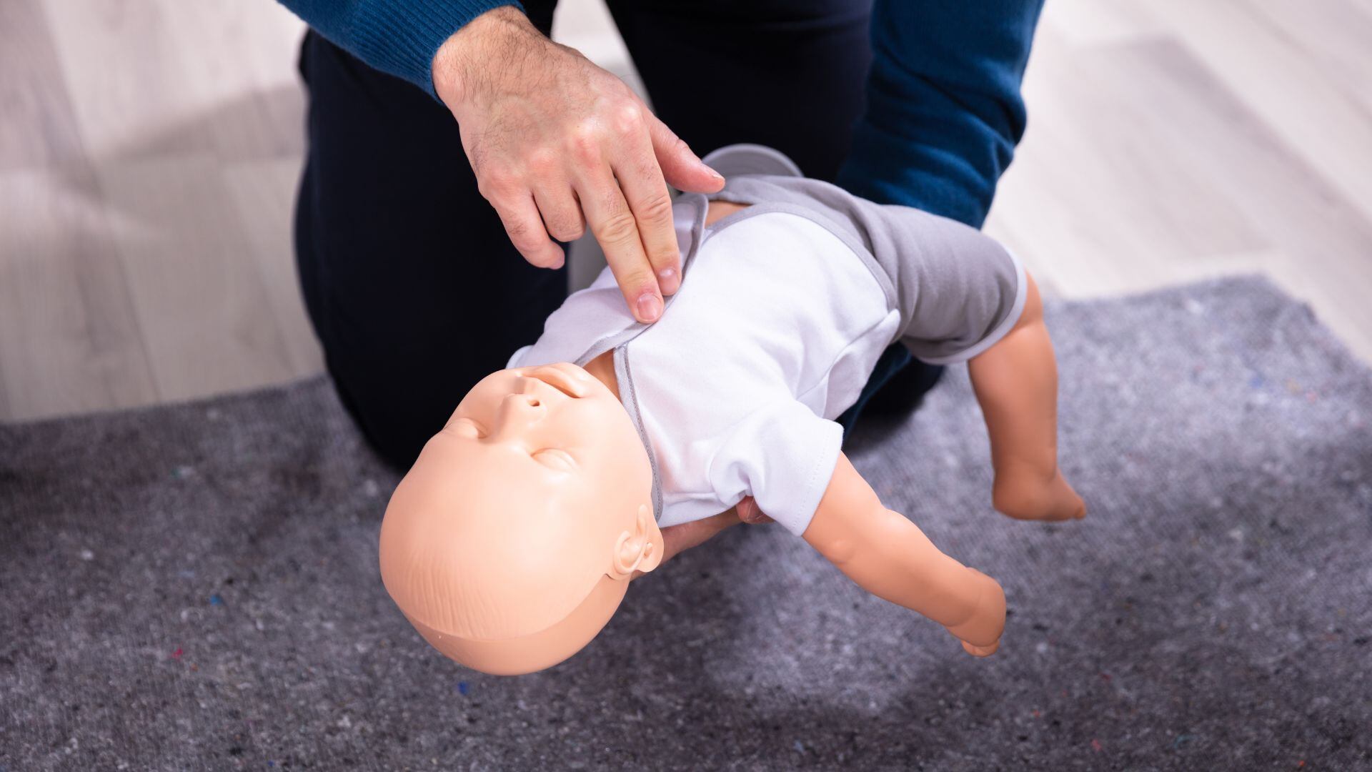 Una persona realiza primero auxilios a un muñeco con forma de bebé. (Canva)
