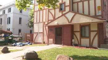 Fachada de un edificio estilo tudor con entramado de madera, una puerta de entrada, césped y contenedores de basura al lado