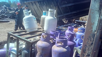 Vista de bomberos retirando cilindros de gas de diferentes tamaños y colores, incluyendo YPF Gas, de una zona afectada por un incendio con escombros