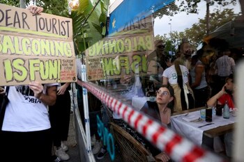 Una turista observa mientras manifestantes