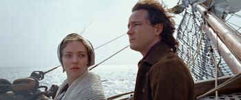 Amanda Seyfried en el centro, brazos extendidos, junto a Lewis Pullman y una congregación en trajes de época, todos con los brazos alzados en una sala iluminada