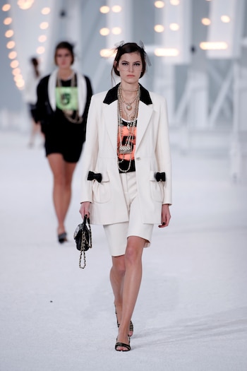 Los esmoquin de bermudas, una sorpresa para la pasarela. Bicolor en off white y negro, con muchos accesorios y el detalle un fascinator con red