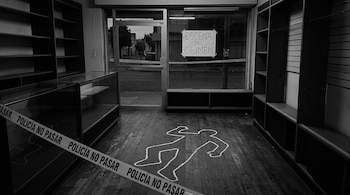 Fotografía en blanco y negro del interior de una tienda vacía con una silueta de tiza en el suelo, estantes y cinta de la policía.