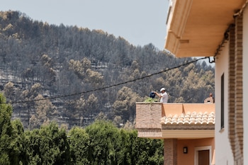 Un vecino riega las plantas de su terraza en Artana (Castellón), uno de los municipios afectados por el incendio declarado el pasado sábado en la Vall d'Uixó (Castellón). (EFE/Manuel Bruque)