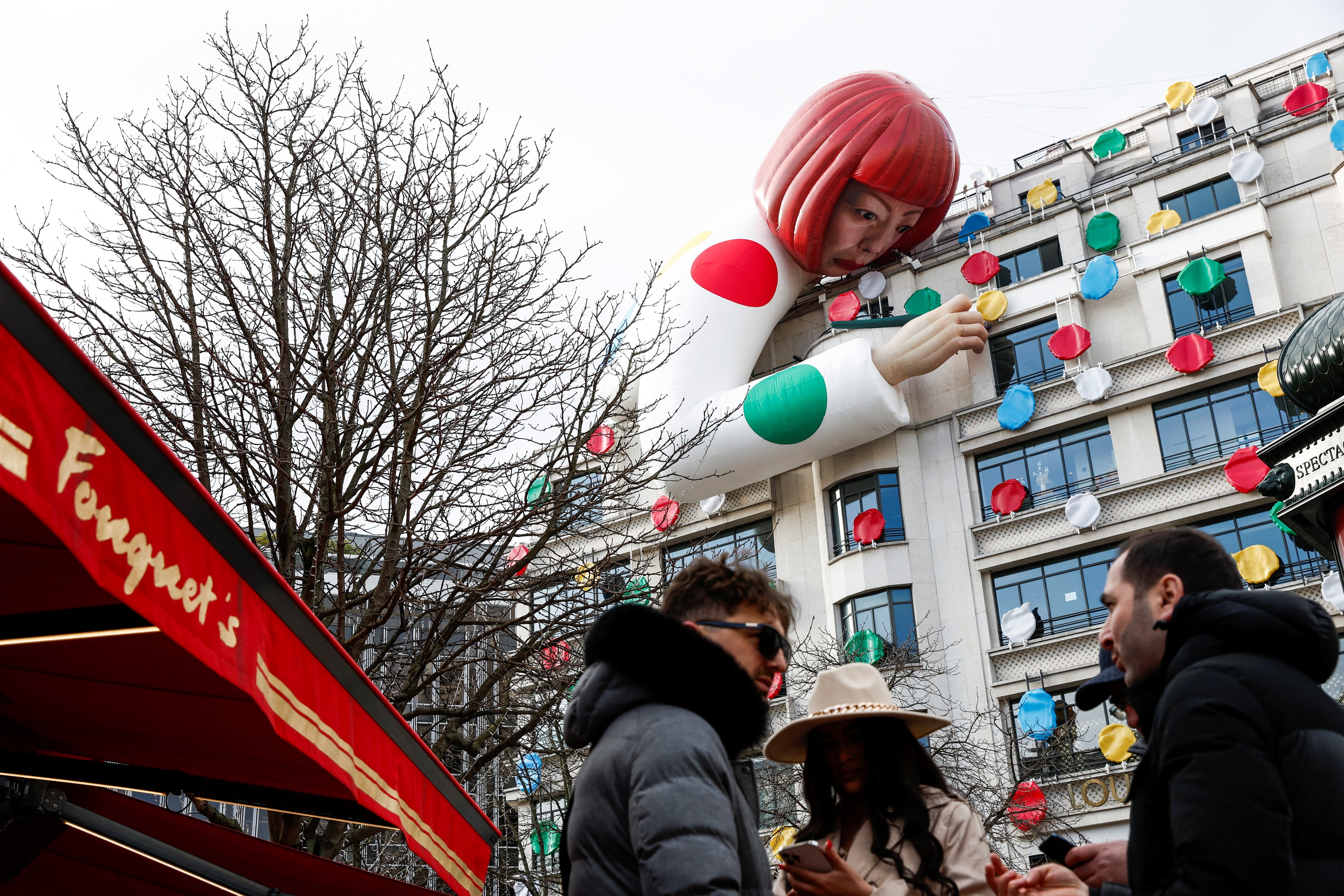 Instalación de un gran maniquí inflable que representa a la artista japonesa Yayoi Kusama, asomándose sobre la tienda insignia de Louis Vuitton en la avenida de los Campos Elíseos de París, Francia (REUTERS/Benoit Tessier)
