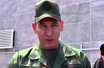 Retrato de un hombre de edad media con uniforme militar verde y gorra frente a una pared