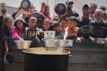 Niños y adultos palestinos esperan