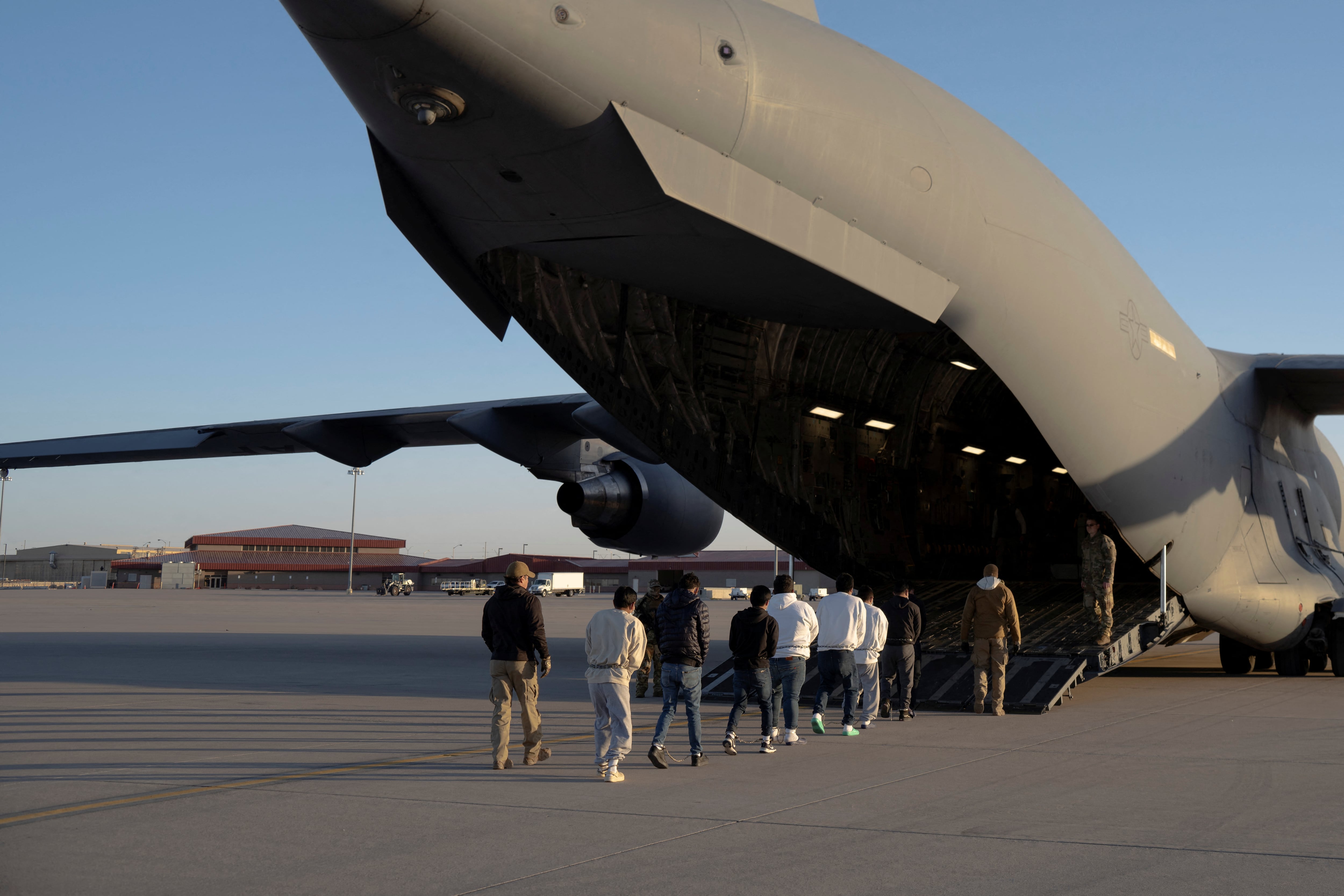 Agentes de seguridad del Servicio de Aduanas y Protección Fronteriza de EE. UU. guían a migrantes detenidos para abordar un avión C-17 Globemaster III de la Fuerza Aérea de EE. UU. para un vuelo de deportación en Fort Bliss, Texas, EE. UU., el 23 de enero de 2025. Departamento de Defensa/Sargento de primera clase del Ejército de EE. UU. Nicholas J. De La Pena/Imagen cedida a través de REUTERS