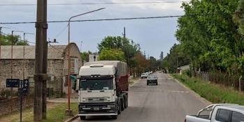 Calle de Rosario con un camión blanco de frente, edificios de ladrillo a la izquierda y árboles a la derecha, bajo un cielo gris