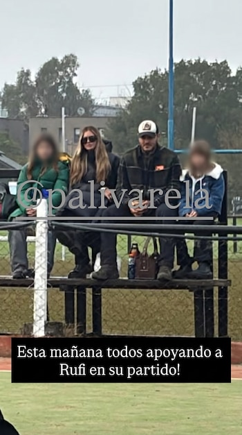 Cuatro personas sentadas en gradas al aire libre, con dos adultos en el centro y dos niñas con rostros borrosos a los lados, en un campo deportivo.