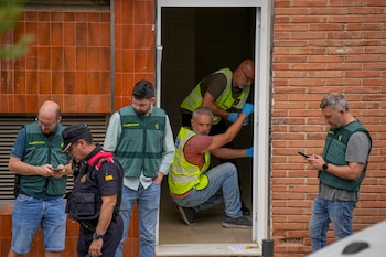 Agentes de la Guardia Civil y policías con chalecos reflectantes y guantes azules examinan el marco de una puerta