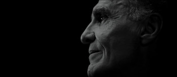 Primer plano en blanco y negro del perfil derecho de un hombre mayor. Se aprecian su ojo, nariz, boca y oreja sobre un fondo oscuro