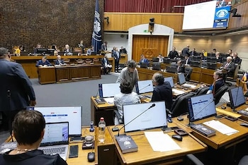 Interior de una sala legislativa en Chile con legisladores sentados en escritorios, equipados con monitores y micrófonos. Se observa una gran pantalla y la bandera chilena