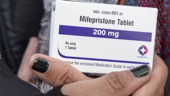 Cerca de una mano sosteniendo una caja blanca de medicamento con la etiqueta 'Mifepristone Tablet 200 mg' y el logo de GenBioPro