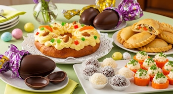 Mesa festiva de Pascua con rosca decorada, huevos de chocolate oscuro, empanadas, trufas de chocolate y coco, y bocaditos de zanahoria y queso crema.