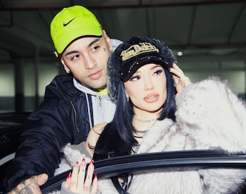Tiago PZK con gorra verde y campera junto a La Joaqui con gorro negro y abrigo de pelo junto a la ventanilla de un automóvil