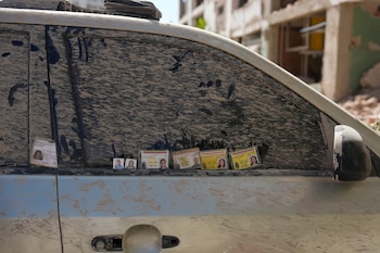 Familiares que buscan información en Catia La Mar, Venezuela, dejan tarjetas de identificación y fotografías de personas desaparecidas en la ventanilla de un auto cubierto de tierra el sábado 27 de junio de 2026, tres días después de que dos terremotos sacudieran el país. (AP Foto/Fernando Vergara)