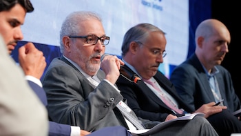 Un hombre con barba y gafas habla en un micrófono en un panel durante la Convención automotriz del Mercosur en Buenos Aires