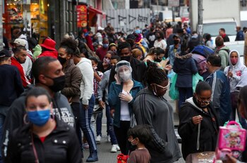 Una mujer con una máscara y un protector facial habla por teléfono mientras la gente camina en una popular calle comercial en medio del brote de COVID-19, en San Pablo, Brasil. 15 de julio de 2020. REUTERS/Amanda Perobelli