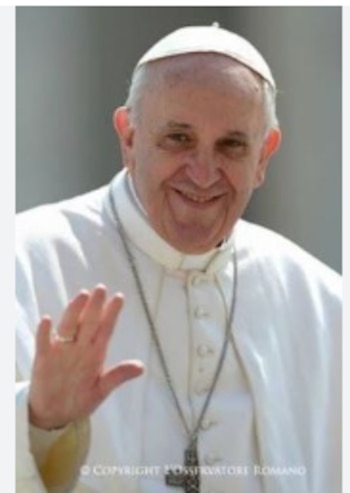 Primer plano del Papa Francisco, vistiendo sotana blanca y solideo, sonriendo y saludando con la mano derecha levantada. Lleva un pectoral