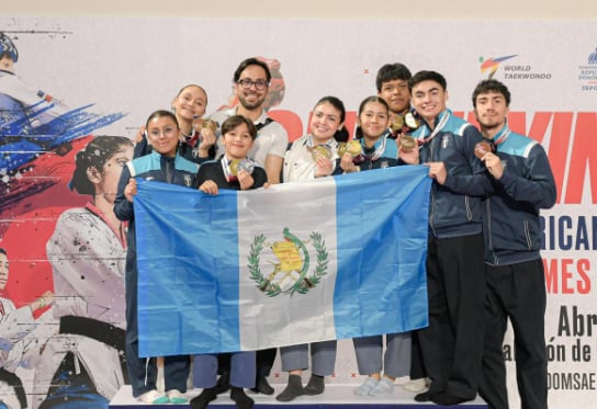 La delegación guatemalteca de Poomsae posa con la bandera y sus medallas tras una histórica jornada en el Open de República Dominicana 2026 (Foto cortesía Taekwondo Guatemala).