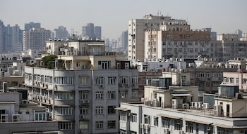 Vista aérea de edificios con numerosas unidades exteriores de aire acondicionado en paredes y tejados, ventanas, antenas y algunas plantas verdes en azoteas.
