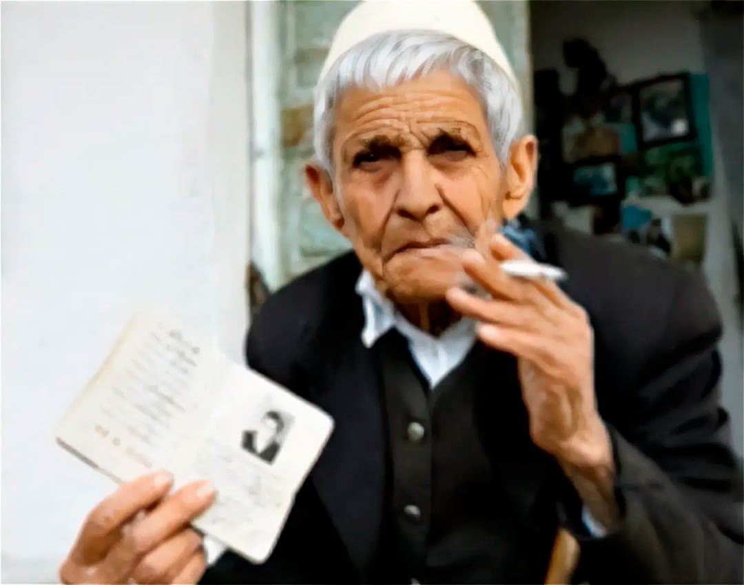 Una virgen jurada de Albania sostiene un documento de identidad abierto mientras fuma un cigarrillo.