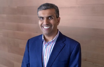 Anil Chakravarthy, un hombre de mediana edad con cabello oscuro y canoso, sonríe a la cámara vistiendo un blazer azul marino y una camisa de rayas de colores