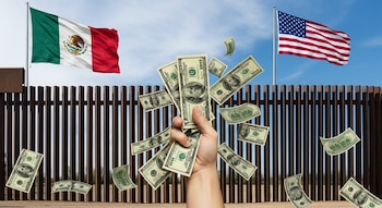 Una mano sujetando y soltando dólares, con billetes flotando. Al fondo, una valla fronteriza de metal y las banderas de México y Estados Unidos.