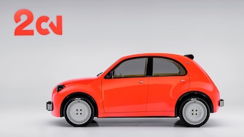 Un automóvil de color naranja visto de perfil sobre un fondo blanco con un logotipo rojo en la pared del fondo