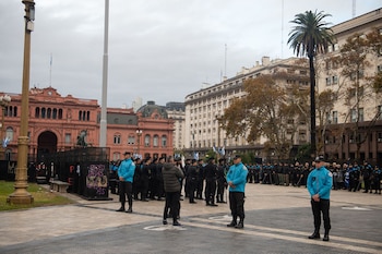 Vista de la Plaza de Mayo con agentes de policía formados en primer plano, la Casa Rosada al fondo y edificios urbanos bajo un cielo nublado